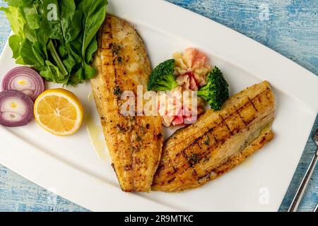 Gegrilltes Seebarschfilet mit Garnierungen in einem eleganten Restaurant Stockfoto