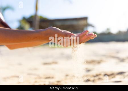 Nahaufnahme der Hände einer birassischen Frau, die am sonnigen Strand mit Sand spielt Stockfoto