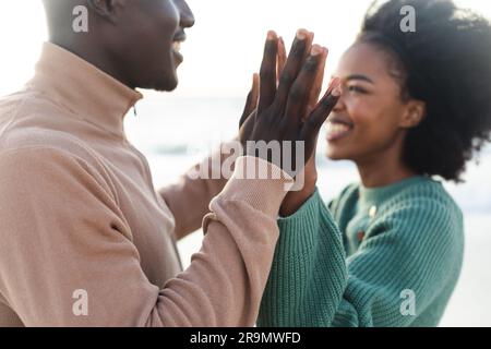 Glückliches afroamerikanisches Paar, das Händchen hielt und am Strand lächelte Stockfoto