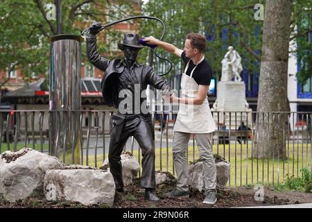 Eine lebensgroße Bronzestatue der Figur Indiana Jones, die gereinigt wird, während sie als neueste Ergänzung der Statue „Scenes in the Square“ auf dem Leicester Square enthüllt wird. Sie verewigt den Helden, den Harrison Ford mit seiner Peitsche und seinem Fedora aus dem Film „Jäger der verlorenen Arche“ von 1981 spielte. Bilddatum: Mittwoch, 28. Juni 2023. Stockfoto