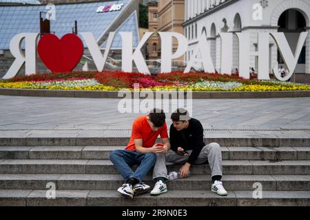 Kiew, Ukraine. 27. Juni 2023. Jungs mit Smartphones sitzen am Maidan Nezalezhnosti (Independence Square) in Kiew, Ukraine, 26. Juni 2023. Kredit: Ondrej Deml/CTK Photo/Alamy Live News Stockfoto