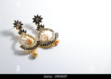 Strahlende Eleganz: Künstliches Gold für Damen Jumka-Schmuck glänzt auf weißer Leinwand Stockfoto