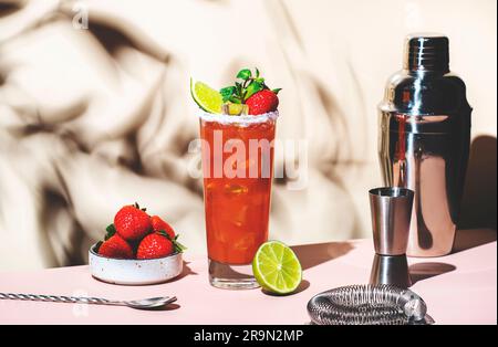 Paloma Cocktailgetränk mit Silbertequila, Grapefruit- und Limettensaft, frischen Erdbeeren, Minze und Eis im Glas mit Salzrand. Beigefarbener rosafarbener Hintergrund., Stockfoto