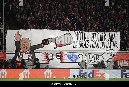 EINGEREICHT - 08. März 2023, Bayern, München: Fußball: Champions League, Bayern München - Paris Saint-Germain, Knockout-Runde, 16. Runde, zweite Etappe, Allianz Arena: Fans halten ein großes Banner mit einem bemalten Uli Hoeneß mit gestrecktem Mittelfinger und einem Hackmesser, der einen Arm abschneidet. Auf Französisch heißt es: "Notre boucher abat le bras long du Qatar", übersetzt in etwa: "Unser Metzger schlachtet den langen Arm von Katar". Der FC Bayern München beendet seine kontroverse Zusammenarbeit mit der Fluggesellschaft Qatar Airways. Der Sponsoringvertrag, der am 30. Juni ausläuft, wird nicht verlängert, der deutsche Fußballrekordmeister Stockfoto