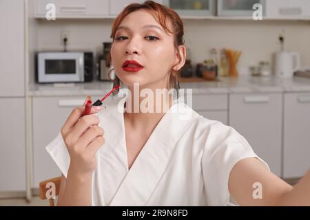 Transgender-Frau, die Selfie nimmt, nachdem sie roten Lippenstift aufgetragen hat Stockfoto