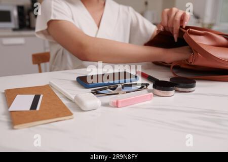 Abgeschnittenes Bild einer Frau, die Sachen aus ihrer Tasche nimmt und auf den Schreibtisch legt Stockfoto