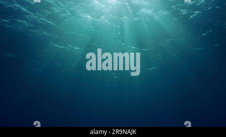 Blick auf Sonnenlicht aus blauem Abgrund, Zeitlupe. Das Licht filtert durch blaues Wasser nach unten. Unterwassersonnenstrahlen im tiefen Ozean. Unterwasser-Sonnenlicht scheint Stockfoto