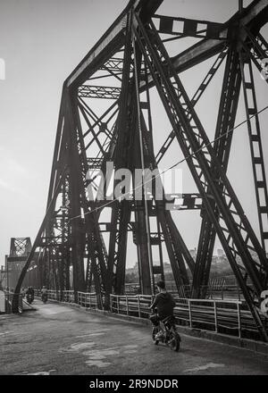 Motorradverkehr überquert die gemeinsame Straße und Eisenbahnbrücke, auch bekannt als Long Bien Bridge in der Dämmerung in Hanoi, Vietnam. Die Brücke stammt aus dem Jahr 1903 und W. Stockfoto