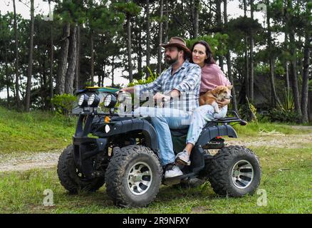 Porträt eines jungen Ehepaars, das auf einem Quad im Wald sitzt Stockfoto