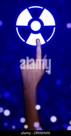 Frau, die das Symbol eines leuchtenden Strahlungswarnsymbols auf blauem Hintergrund mit verschwommenem Licht berührt, Nahaufnahme Stockfoto