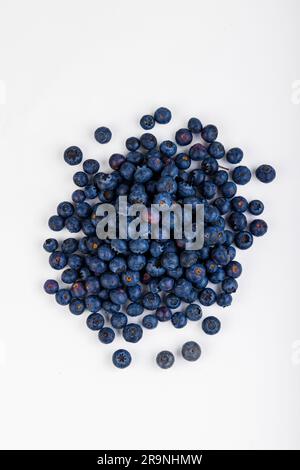 Ein Haufen frisch geernteter süßer und saftiger Blaubeeren auf einem weißen Tisch, bereit zum Genießen Stockfoto