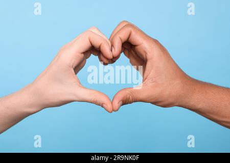 Internationale Beziehungen. Menschen machen Herz mit Händen auf hellblauem Hintergrund, Nahaufnahme Stockfoto