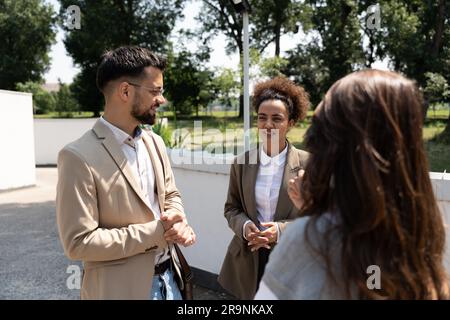 Eine Gruppe von Kollegen, die vor den Bürogebäuden gehen, besprechen den Geschäftsplan. Geschäftsleute, die über Ideen und m Stockfoto