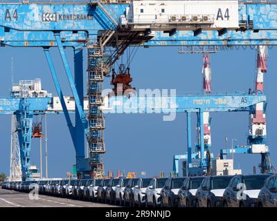 Schlangen von gerade eingetroffenen importierten Autos am Hafen in Haifa, Israel, warten auf Lieferung und Umladung. Wir können auch einige der massiven Gantry sehen Stockfoto