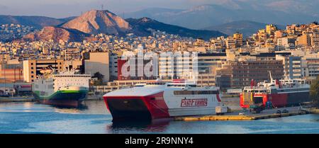 Piräus ist eine geschäftige mediterrane Hafenstadt im Stadtgebiet von Athen in der griechischen Region Attika. Hier sehen wir es bei Sonnenuntergang, von unserem cr aus gesehen Stockfoto