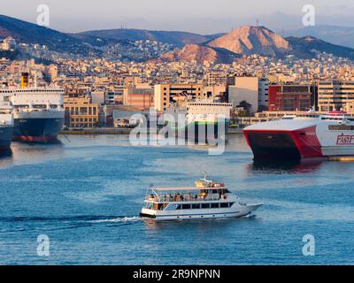 Piräus ist eine geschäftige mediterrane Hafenstadt im Stadtgebiet von Athen in der griechischen Region Attika. Hier sehen wir es bei Sonnenuntergang, von unserem cr aus gesehen Stockfoto