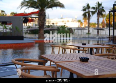 Holztische und -Stühle am Pool im Hotel Stockfoto