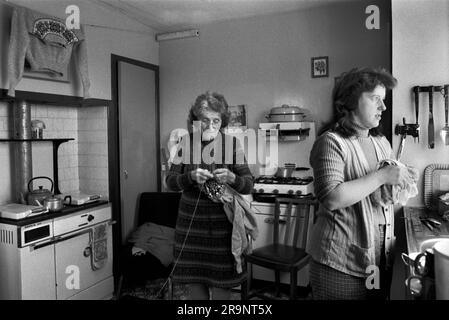 Strickpullover mit Norwegermuster. Eine zuchtende Familie, Mutter und Tochter in ihrer Küche. Die ältere Frau strickt einen Fair-Isle-Pullover, einer wurde gewaschen und zum Trocknen über dem Herd aufgehängt, bevor er in einem Geschäft vor Ort verkauft wird. Shetlands Festland, Shetland Islands, Schottland, ca. 1979. UK 1970S HOMER SYKES Stockfoto