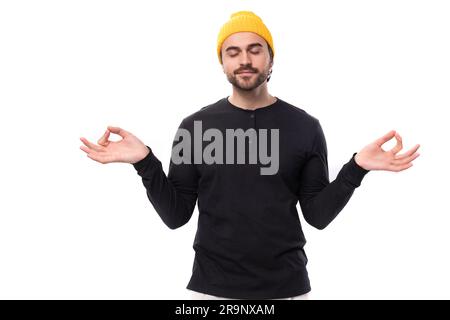 Junger brünetter europäischer brutaler Mann in schwarzer Jacke meditiert Stockfoto