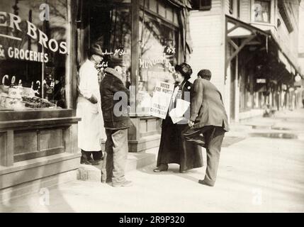 Ein amerikanischer Suffragist, der mit einem Lebensmittelhändler in Branford, New York, Kalifornien, spricht. 1915. Stockfoto