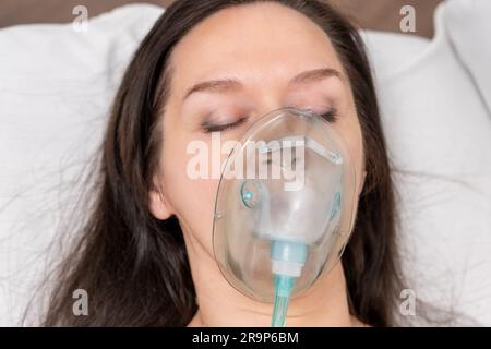 Eine Erwachsene Frau liegt in einer Sauerstoffmaske auf einem Krankenhausbett und wird behandelt. Stockfoto