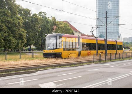 warschau, polen. 17. juni 2023: Erleben Sie effizienten städtischen Transport mit warschaus lebhaften gelben Straßenbahnen, die nahtlos durch den Verkehr A navigieren Stockfoto