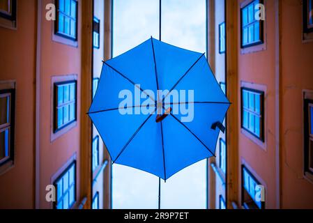 Farbenfrohe Sonnenschirme schmücken eine enge Straße zwischen alten gelben europäischen Gebäuden. Bunte Sonnenschirme sorgen für eine festliche, lustige Kulisse in Wien Stockfoto
