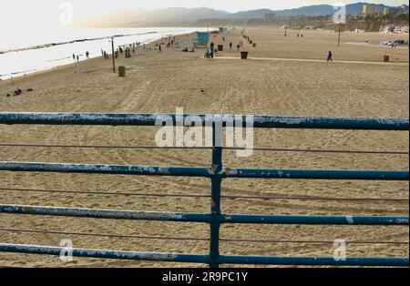 Rettungsschirme und Menschen am Santa Monica State Beach vom Santa Monica Pier aus gesehen mit Geländer Kalifornien USA Stockfoto