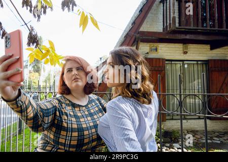 Zwei elegante junge Latina-Frauen, Freunde argentinischer Herkunft, stehen mittags vor ihrem Haus in einem Viertel in der Provinz Buenos A. Stockfoto