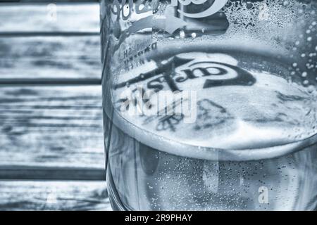 Moody kalt getöntes Monochrom von Carlsberg-Bierglas auf Biergartentisch bei nachmittäglicher Sonneneinstrahlung. Siehe Hinweise zum Fokuspunkt. Eiskälte in Alex Pun Stockfoto