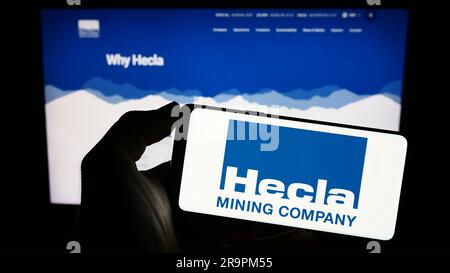 Person, die ein Smartphone mit dem Logo des US-amerikanischen Unternehmens Hecla Mining Company auf dem Bildschirm vor der Website hält. Konzentrieren Sie sich auf das Display des Telefons. Stockfoto