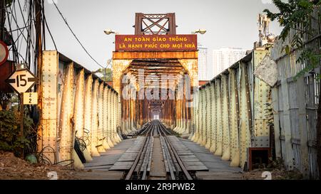 Ein Blick entlang der Bahngleise über die rostige Long Bien Bridge in Hanoi, Vietnam. Auf dem Schild steht: Verkehrssicherheit ist das Glück eines jeden Hauses Stockfoto