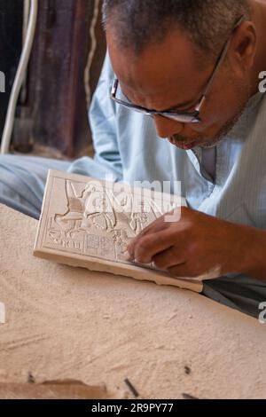 Einheimischer Handwerker, der moderne Souvenirreproduktionen von Basreliefschnitzereien aus dem Leichentempel der Hatschepsut in Deir al-Bahri, Luxor, herstellt Stockfoto