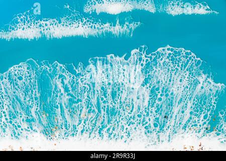 Kunstharzkunst mit blauen Wellen und Sandstrand. Hintergrund mit Meeresmotiv aus Epoxidharz Stockfoto