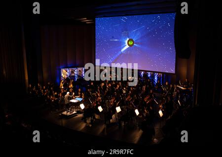 National Philharmonic führt kosmische Zyklen auf: Eine Weltraumsymphonie. Maestro Piotr Gajewski dirigiert die Nationalphilharmonie in der weltbesten Darbietung von Henry Dehlingers "Cosmic Cycles", Donnerstag, 11. Mai 2023, in Capital One Hall in Tysons, Virginia „Cosmic Cycles: A Space Symphony“ ist eine Zusammenarbeit zwischen dem Komponisten Henry Dehlinger, dem Goddard Space Flight Center der NASA, und der National Philharmonic, die in sieben Multimedia-Werken über Sonne, Erde, Mond, Planeten und Kosmos eine Fusion von Musik und Video bietet. Stockfoto