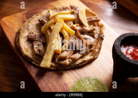 Steak-Taco mit pommes frites. Sehr beliebter Taco de Bistec oder Carne Asada in Mexiko, hausgemachtes Roastbeef auf einer Maistortilla. Ich Stockfoto