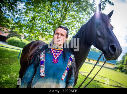 Neu Damerow, Deutschland. 27. Juni 2023. Der 72-jährige „professionelle Indianer“ Wolfgang Kring steht mit seinem Pferd während des Trainings für die jetzt 30. Apache Live Show in der ReitArena. Auf der natürlichen Bühne im Mecklenburger Seengebiet feiert das aktuelle Stück seine Premiere am letzten Wochenende im Juli. An insgesamt drei Wochenenden sind insgesamt sechs Vorstellungen mit rund 30 Amateurdarstellern geplant. Die fiktive Geschichte spielt in der Zeit des beginnenden Amerikanischen Bürgerkriegs in der Mitte des 19. Jahrhunderts. Kredit: Jens Büttner/dpa/Alamy Live News Stockfoto