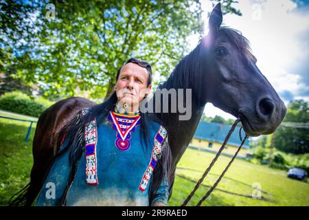 Neu Damerow, Deutschland. 27. Juni 2023. Der 72-jährige „professionelle Indianer“ Wolfgang Kring steht mit seinem Pferd während des Trainings für die jetzt 30. Apache Live Show in der ReitArena. Auf der natürlichen Bühne im Mecklenburger Seengebiet feiert das aktuelle Stück seine Premiere am letzten Wochenende im Juli. An insgesamt drei Wochenenden sind insgesamt sechs Vorstellungen mit rund 30 Amateurdarstellern geplant. Die fiktive Geschichte spielt in der Zeit des beginnenden Amerikanischen Bürgerkriegs in der Mitte des 19. Jahrhunderts. Kredit: Jens Büttner/dpa/Alamy Live News Stockfoto