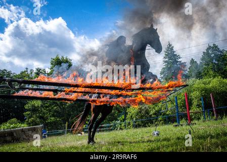 Neu Damerow, Deutschland. 27. Juni 2023. Der 72-jährige „professionelle Indianer“ Wolfgang Kring springt mit seinem Pferd über ein brennendes Hindernis während des Trainings für die jetzt 30. Apache Live Show. Auf der natürlichen Bühne im Mecklenburger Seengebiet feiert das aktuelle Stück seine Premiere am letzten Wochenende im Juli. An insgesamt drei Wochenenden sind insgesamt sechs Vorstellungen mit rund 30 Amateurdarstellern geplant. Die fiktive Geschichte spielt in der Zeit des beginnenden Amerikanischen Bürgerkriegs in der Mitte des 19. Jahrhunderts. Kredit: Jens Büttner/dpa/Alamy Live News Stockfoto