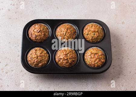 Kürbismuffins mit Haferbrei und Nüssen in einer Backform auf einem beigen strukturierten Hintergrund. Leckere, gesunde, hausgemachte Kuchen. Stockfoto