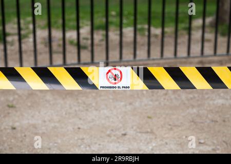 Gelb-schwarz gestreiftes Klebeband mit einem Schild „Zutritt verboten“ mit der Aufschrift „Prohibido el paso“ auf spanisch, was im Englischen „Zutritt verboten“ bedeutet. Stockfoto