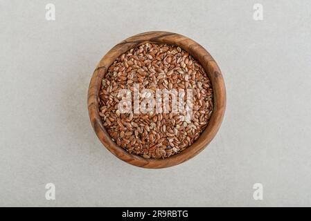 Leinsamen in Holzschüssel auf Betonhintergrund. Draufsicht Stockfoto