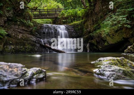 Die Sychryd Cascades oder Sgydau Sychryd Falls mit Holzbrücke im Waterfall Country in der Nähe von Dinas Rock, Pontnedfechan, Brecon Beacons National Park, South Wales, Großbritannien. Wasser mit langer Exposition. Stockfoto