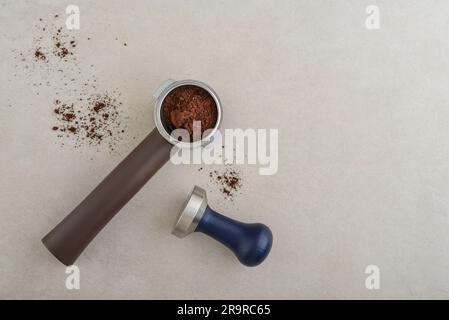 Portafilter mit Kaffee und Temperament auf hellem Betonhintergrund, Draufsicht Stockfoto