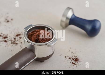 Portafilter mit Kaffee und Temperament auf hellem Betonhintergrund Stockfoto