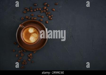 Tasse Kaffee mit Kaffeebohnen auf schwarzem Hintergrund, Draufsicht Stockfoto