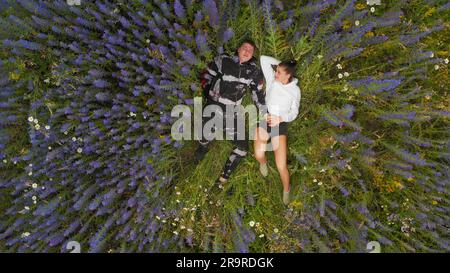 Hübscher Kerl und Mädchen in blühenden Blumen. Ein Kerl und ein Mädchen in Zyanose-Blumen. Ein liebevoller Kerl und ein Mädchen, das in einem Lavendelfeld steht. Stockfoto