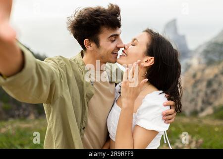 Liebendes junges Paar, das sich anfreundet und Selfie nach der Verlobung macht, mit wunderschönem Blick auf das Meer Stockfoto