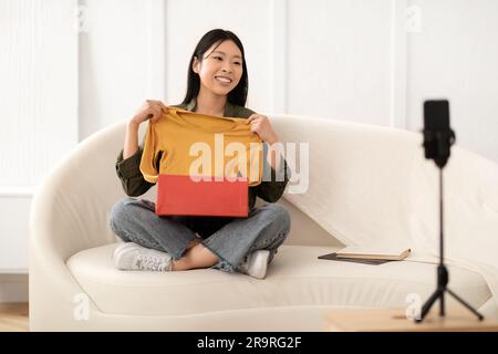 Modebloggerin, junge Asiatin, die Produktwäsche rezensiert, streamt Stockfoto
