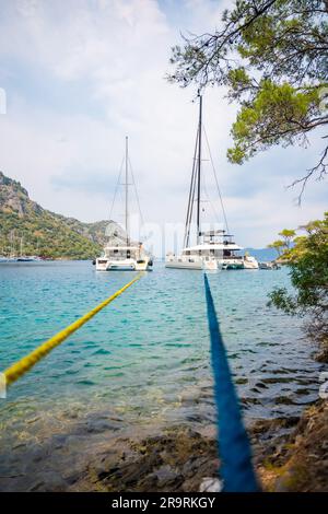 Fethie, Türkei - 4. Juni 2023: Wunderschöne Meeresküste Aquarium Bay nahe Fethie, Türkei. Sommerlandschaft mit Mooryachten, klarem blauem Wasser und Kiefer Stockfoto